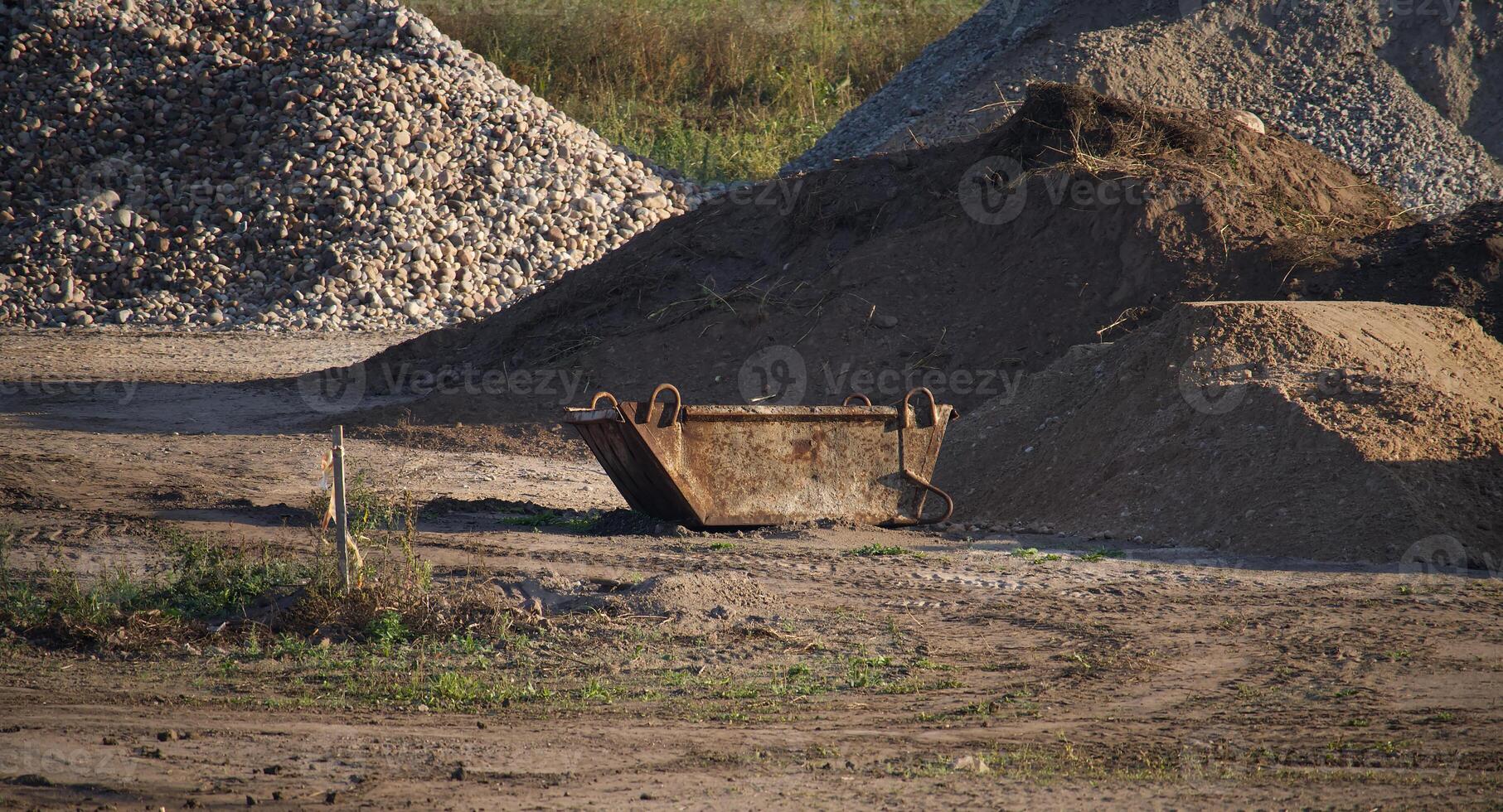 Rusty skip bin in a construction site with piles of gravel and earth, symbolizing industrial work photo