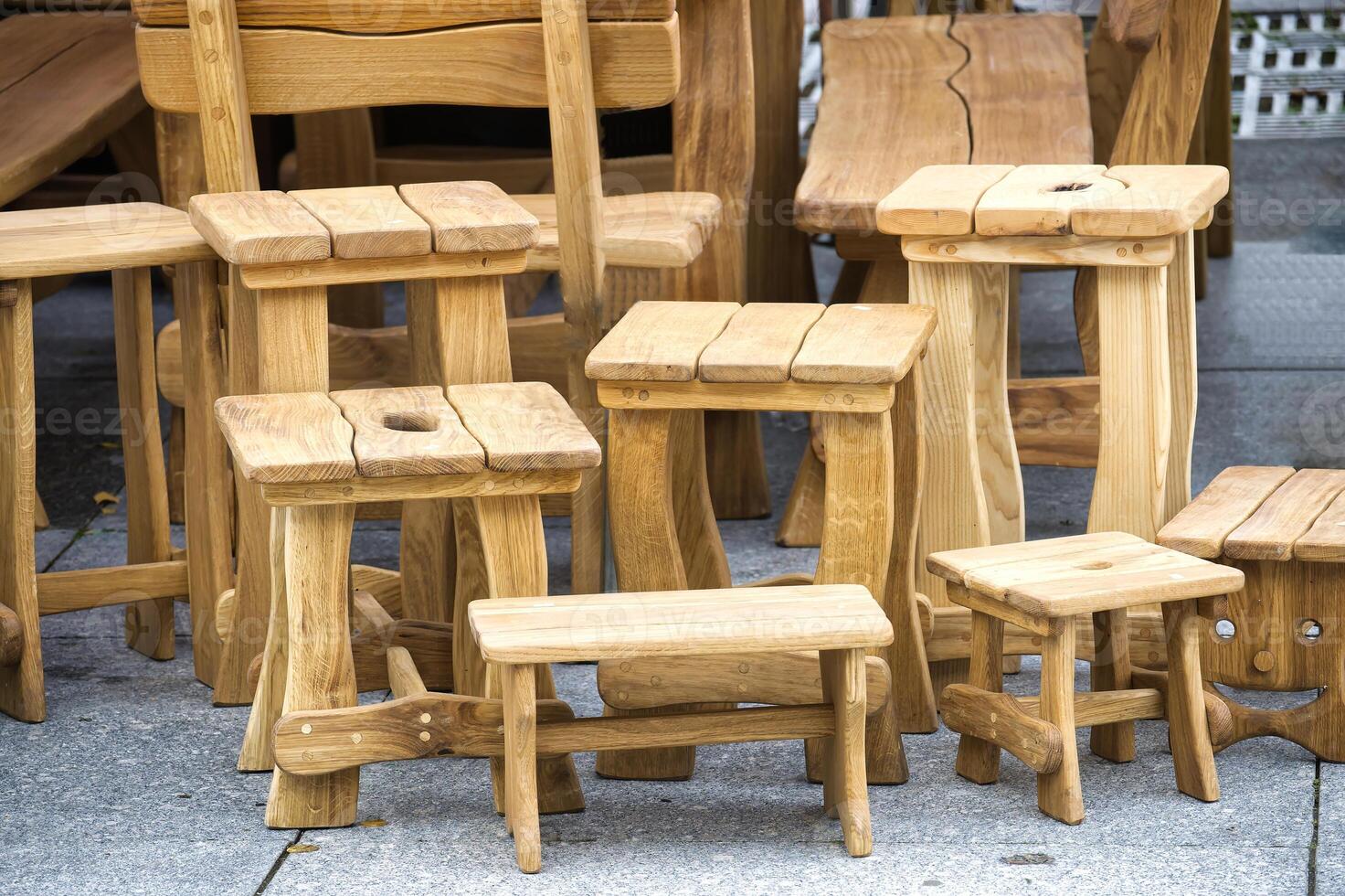 Collection handcrafted wooden stools and benches displayed outdoors showcasing rustic craftsmanship photo