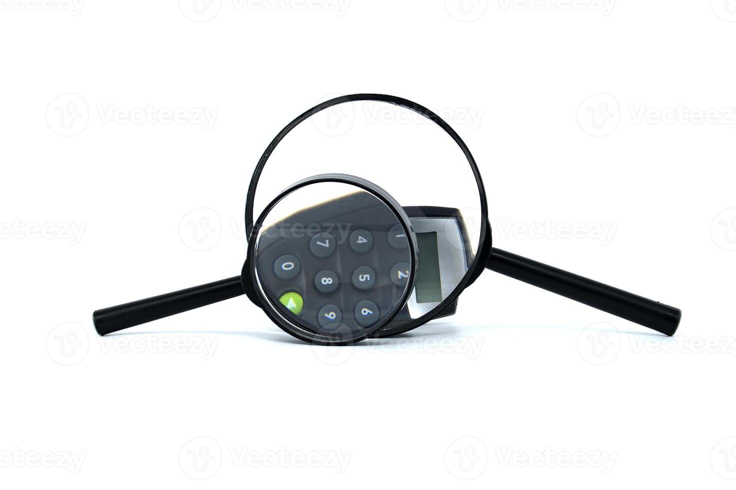 Magnifying glass focuses on calculator keypad symbolizing financial analysis, precision photo