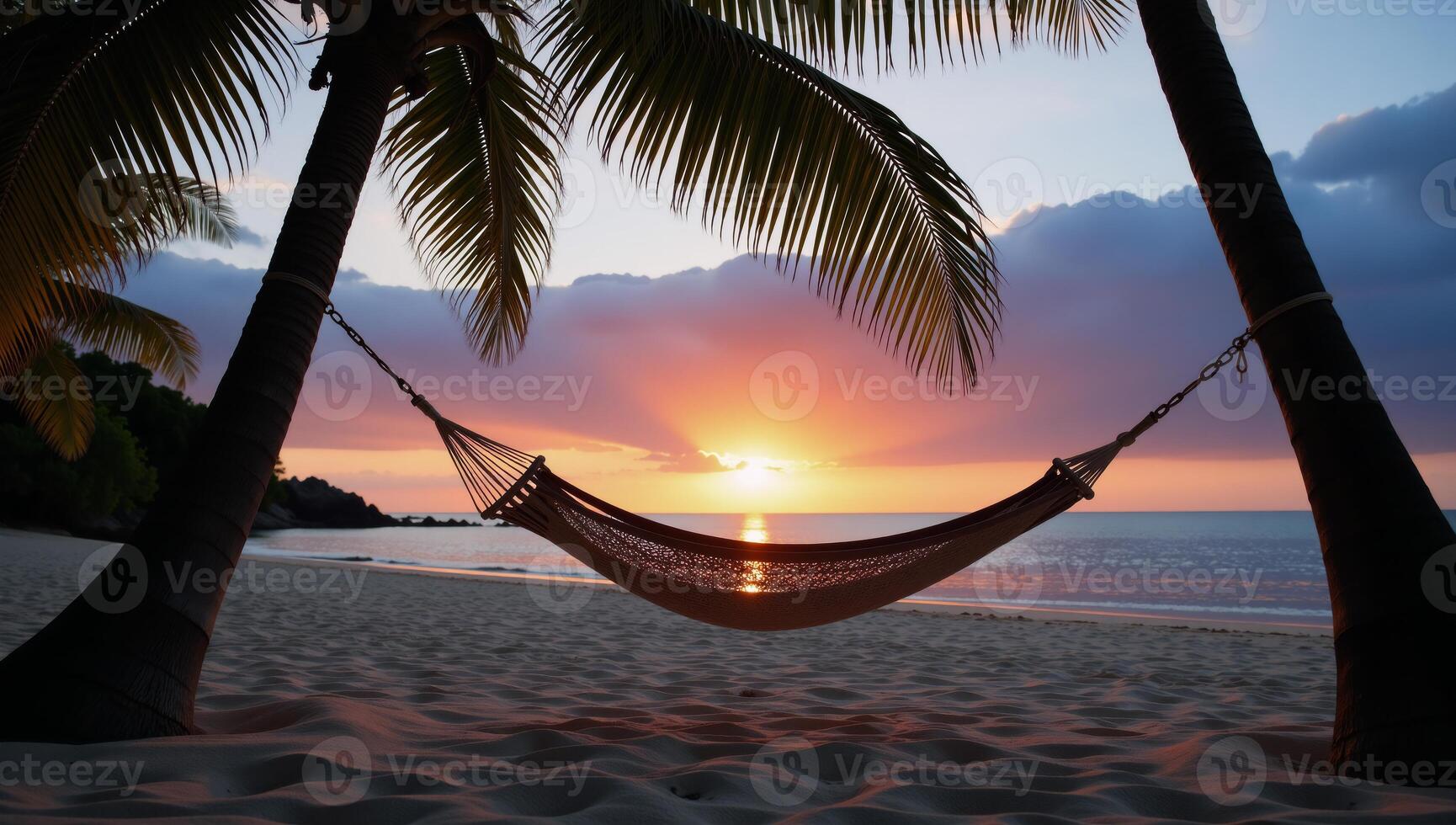 Beach scene featuring silhouetted hammock under palms during sunset photo