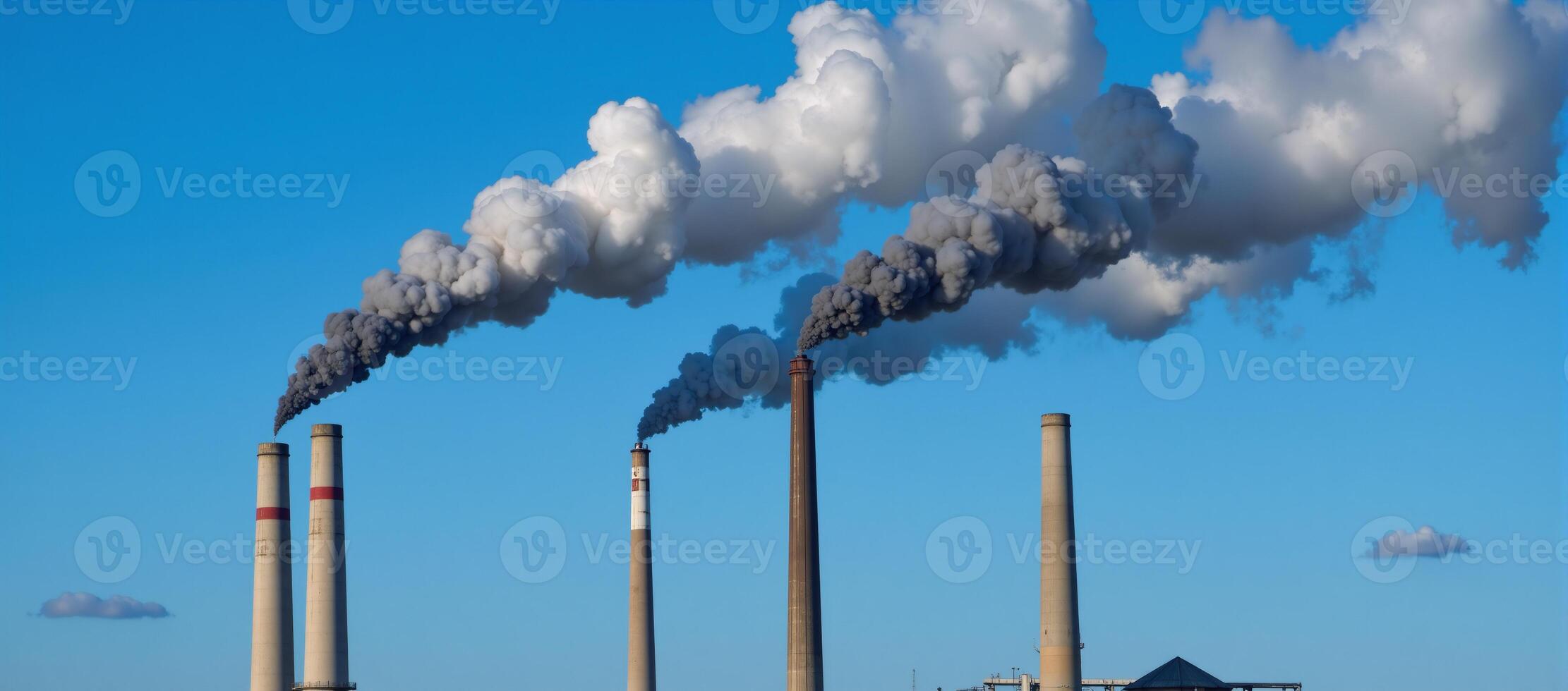 Smokestacks release pollutants against backdrop of clear skies showcasing industrial air pollution effects photo