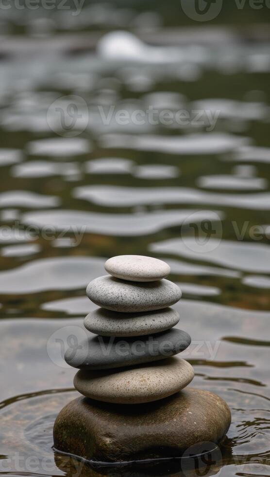 Balanced stack of smooth river stones next to a flowing stream photo