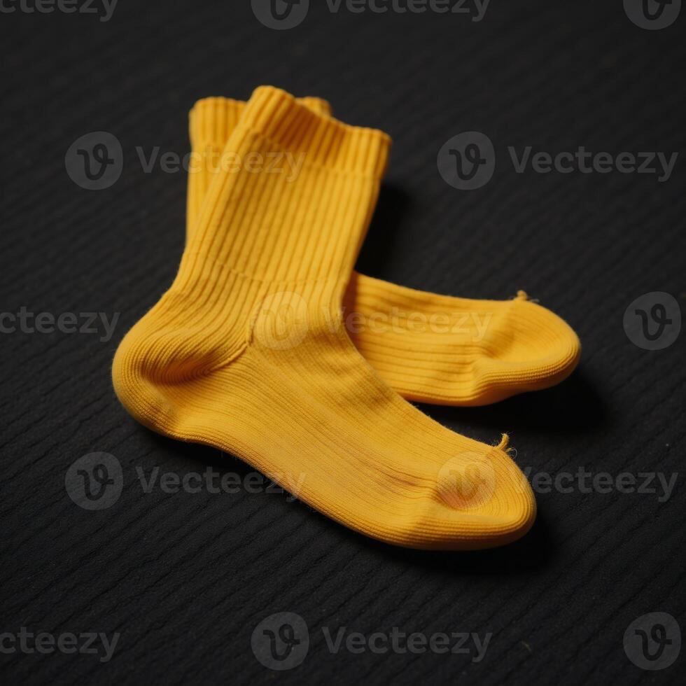 A solitary vibrant yellow sock rests upon a weathered rugged dark background photo