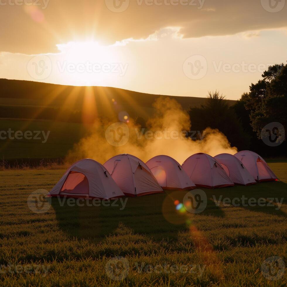 Tents in a field at sunset photo