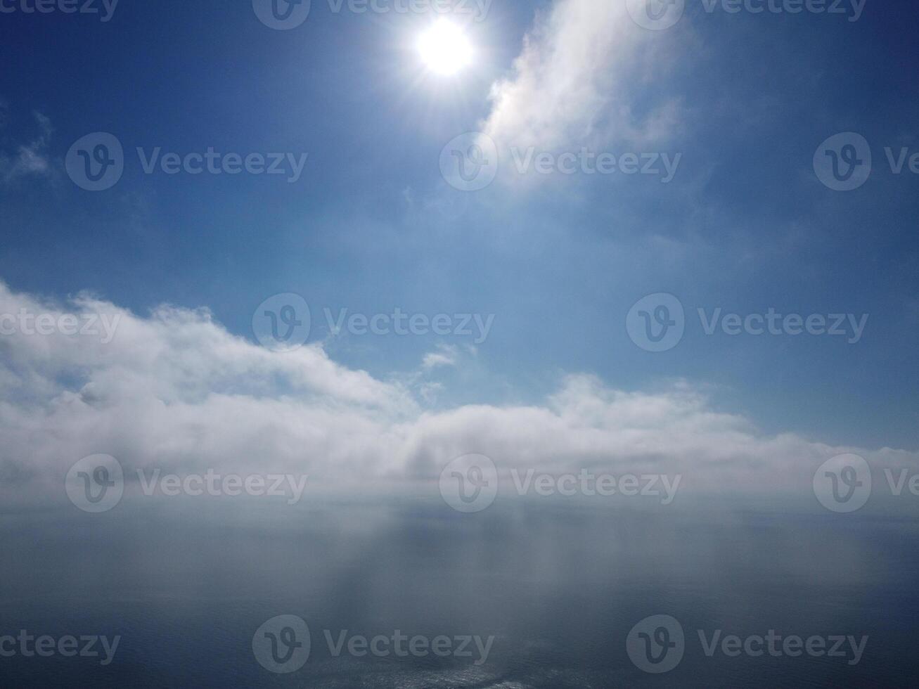 Aerial view. The drone flies over foggy and fluffy clouds. Blue sky sun and sea fog. Abstract aerial nature summer ocean sunset sea and sky background. Vacation, travel and holiday concept photo