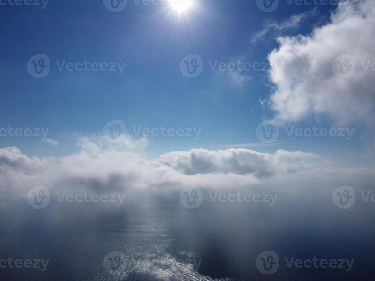 Aerial view. The drone flies over foggy and fluffy clouds. Blue sky sun and sea fog. Abstract aerial nature summer ocean sunset sea and sky background. Vacation, travel and holiday concept photo