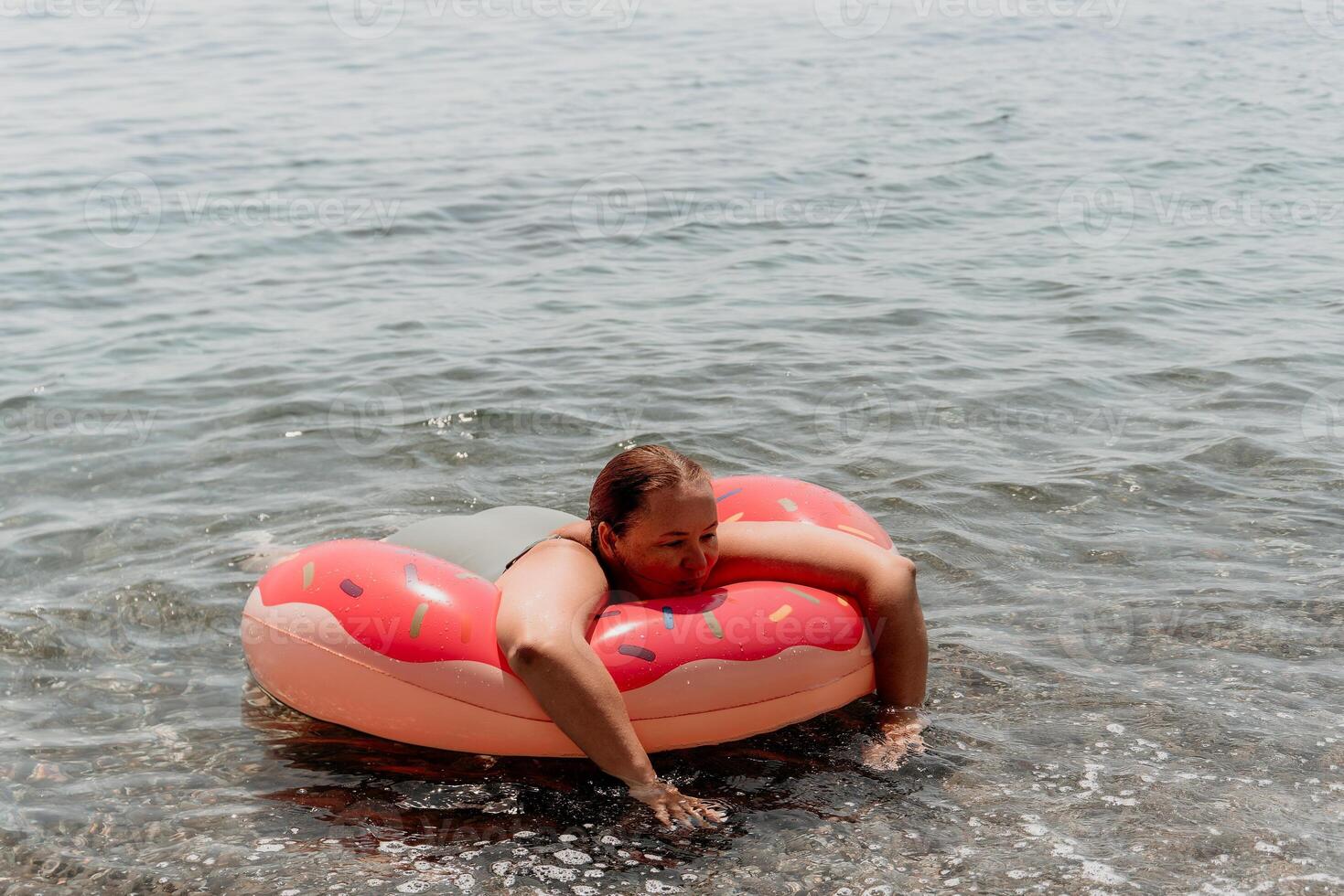 Girl Donut Float Summer Fun Beach - Woman enjoys a relaxing day at the beach on an inflatable donut float. photo