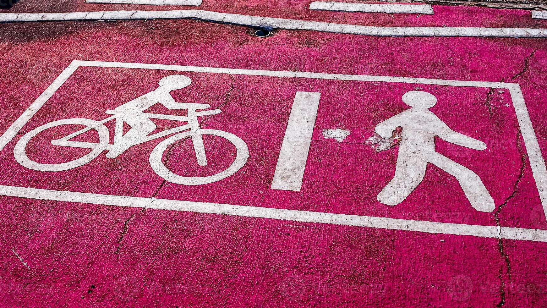 A pink painted road sign with a white sign that says bicycle photo