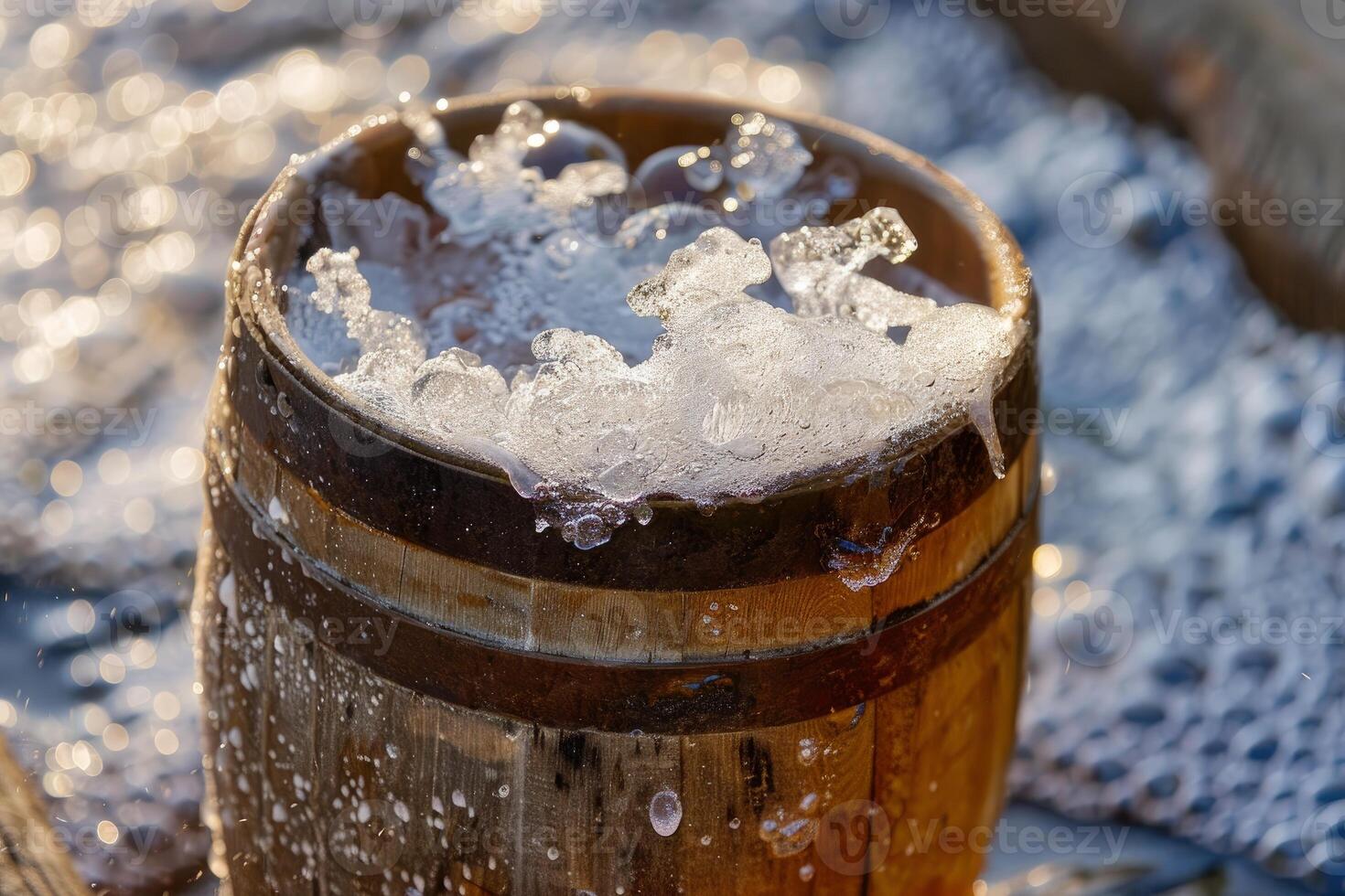 Wooden bucket overflowing with ice cold water on summer day photo