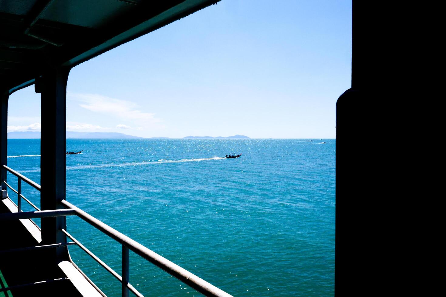 Scenic Ocean View from a Boat Deck with Clear Blue Sky and Distant Mountains photo