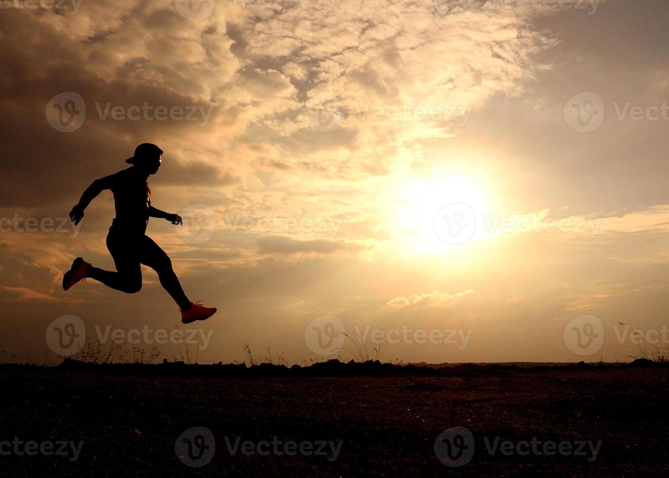 Silhouette of a Person Running at Sunset with Dramatic Sky and Clouds in the Background photo