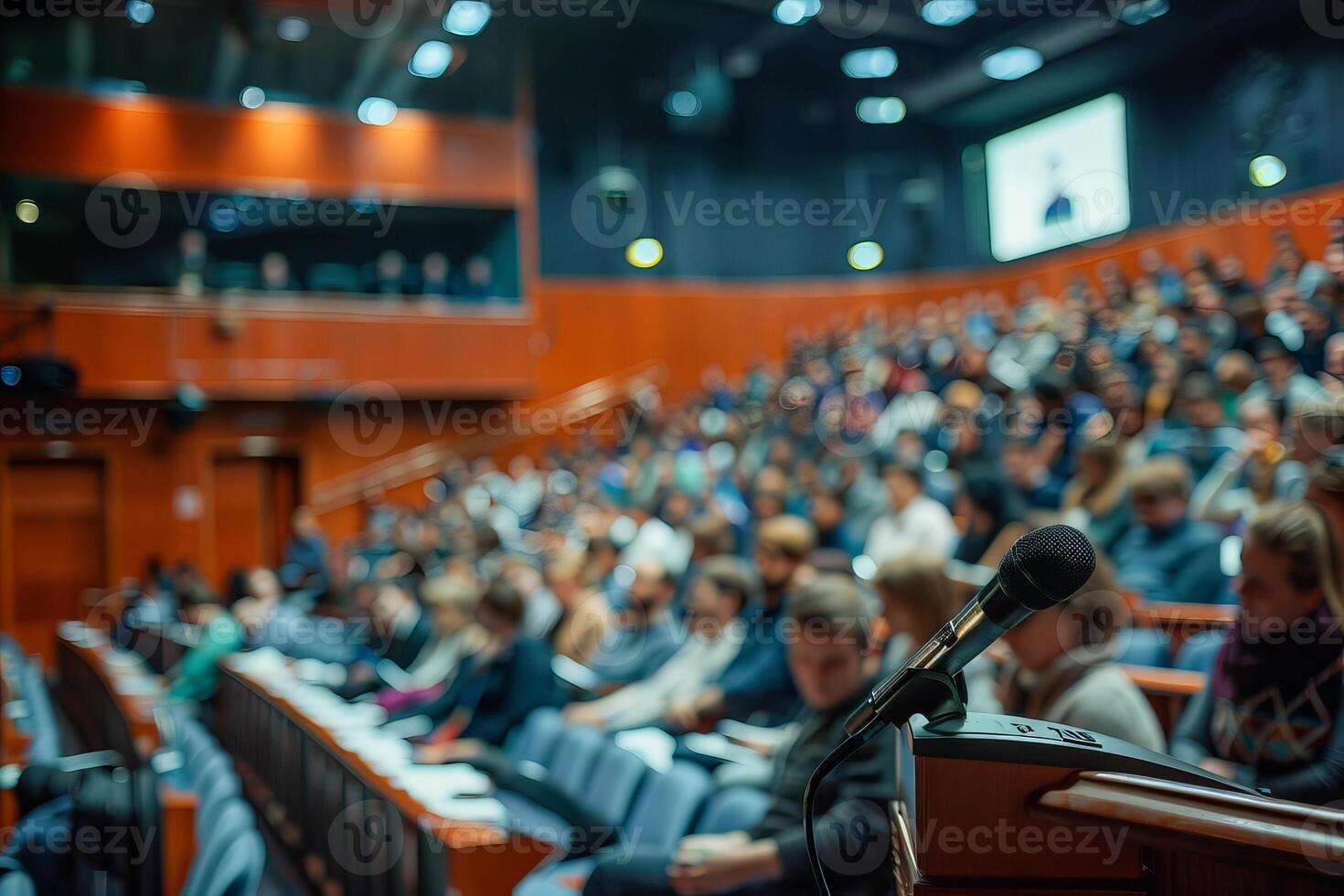 Microphone standing on stage with blurred audience attending a conference in the background photo