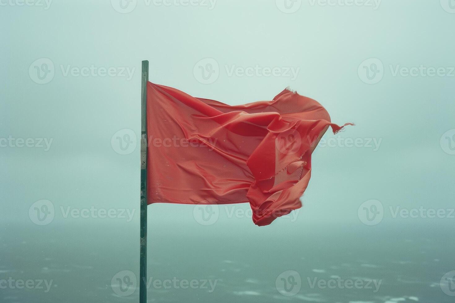 Red warning flag waving in the wind on the coast photo