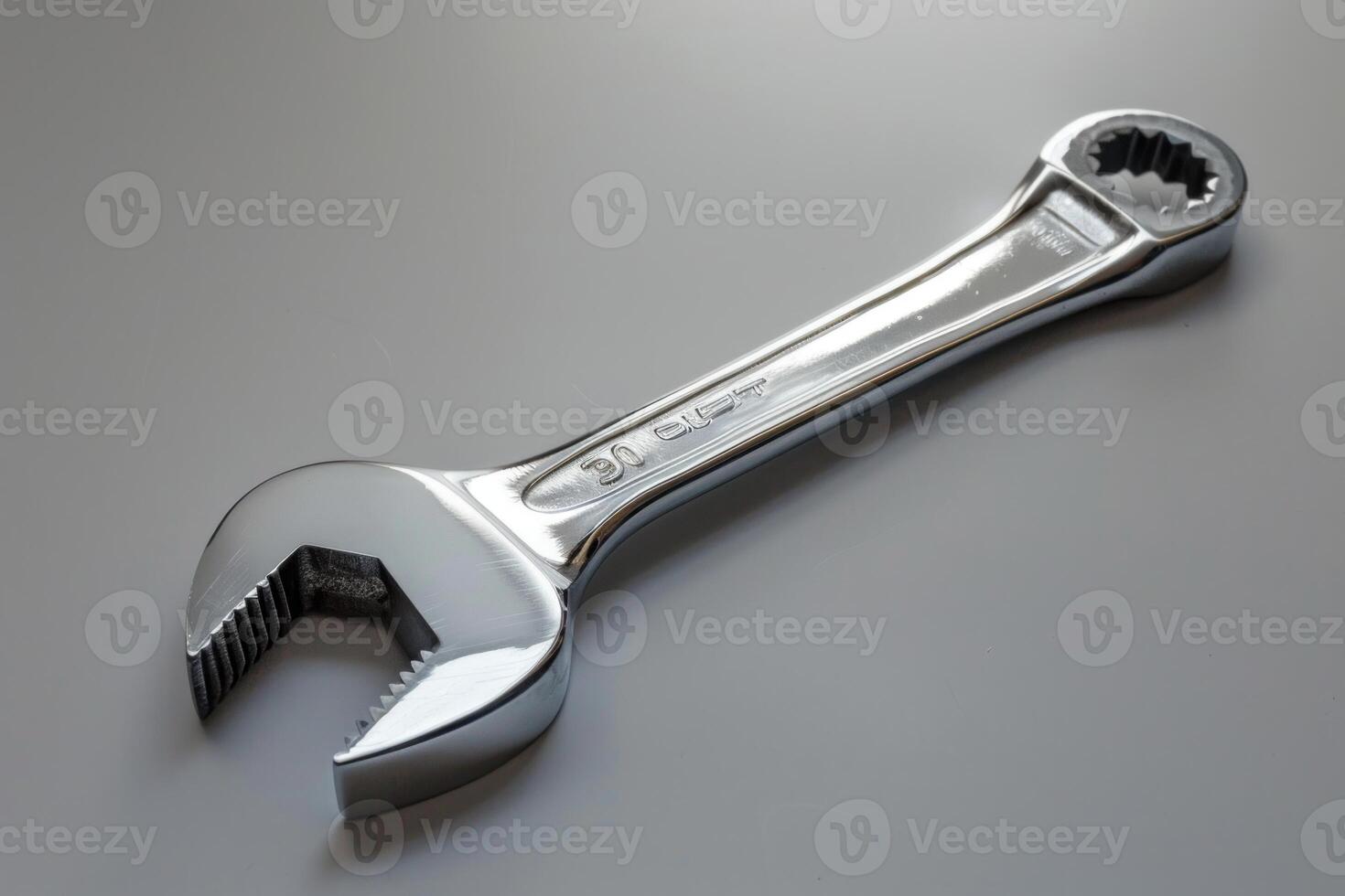 Chrome wrench lying on a grey surface photo