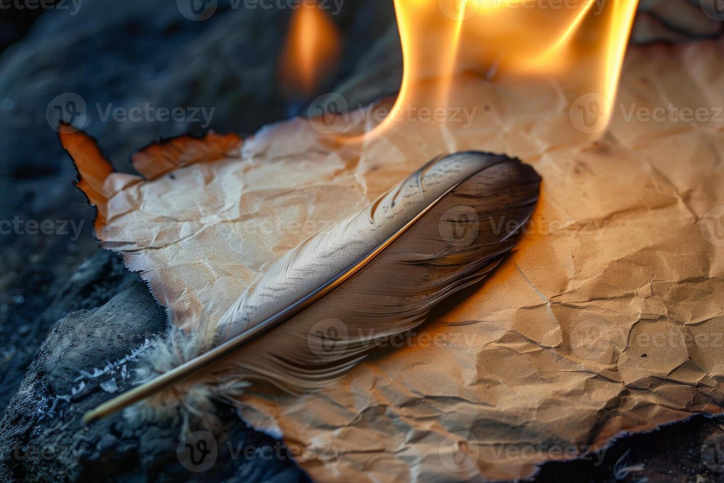 A feather quill rests on a piece of parchment that is being consumed by flames photo
