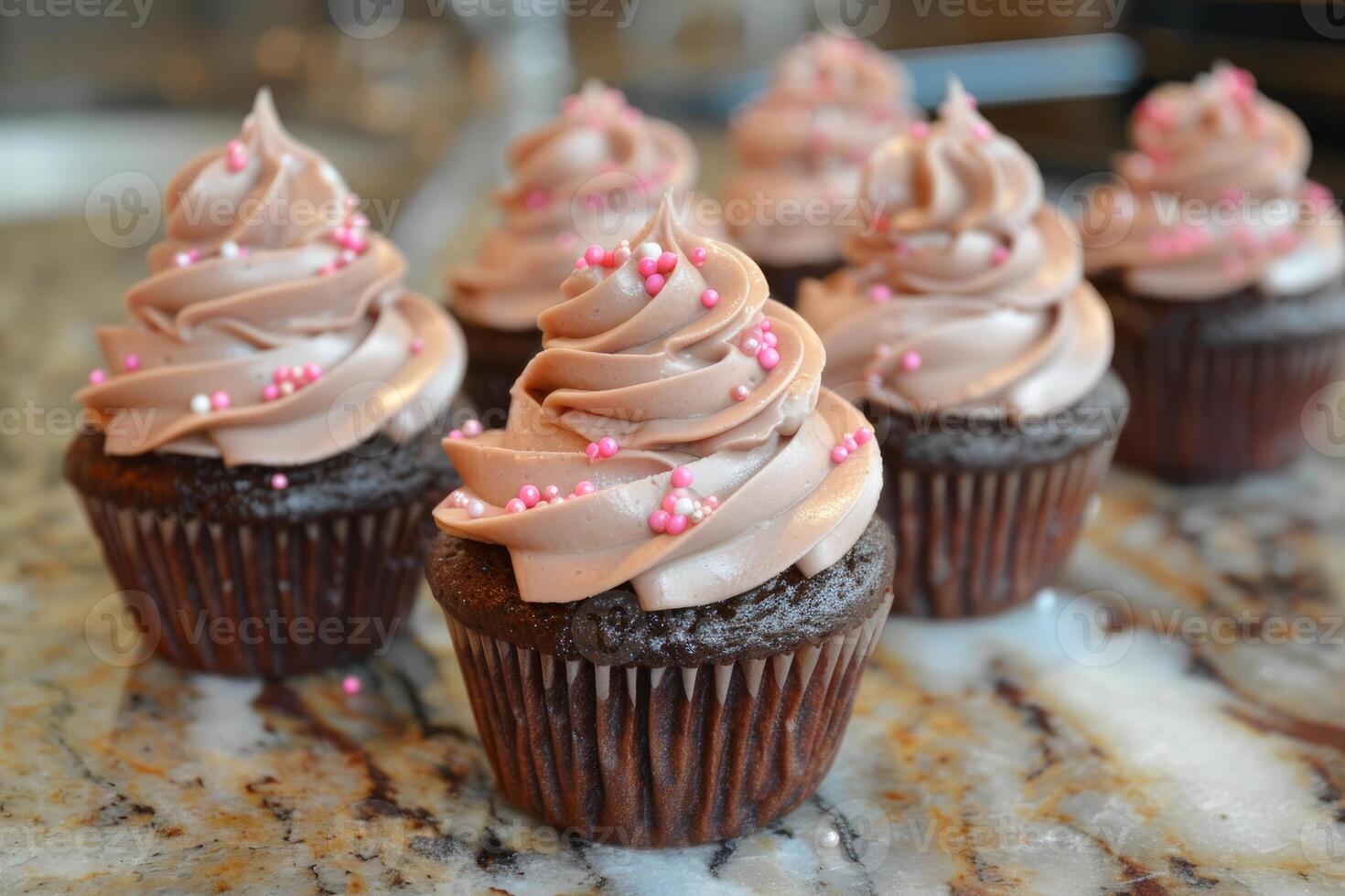 Chocolate cupcakes with chocolate buttercream frosting and pink sprinkles photo