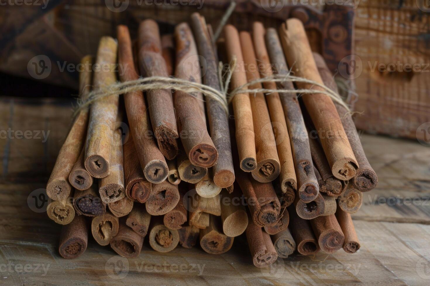 Cinnamon sticks tied together with string lying on rustic wooden surface photo