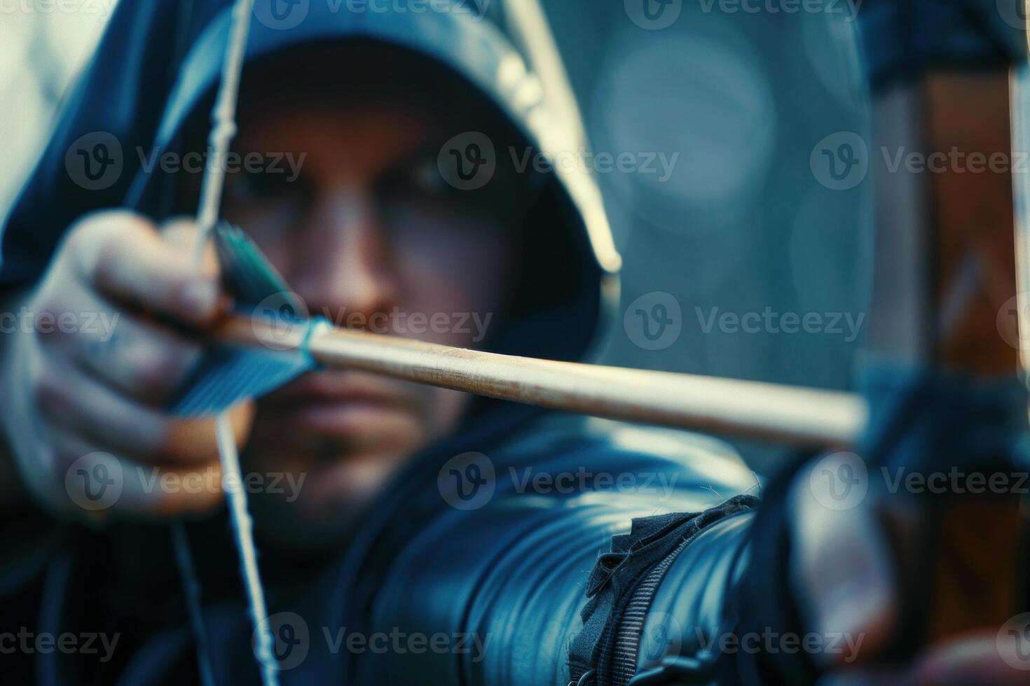 Archer wearing a hood is aiming an arrow at a target photo