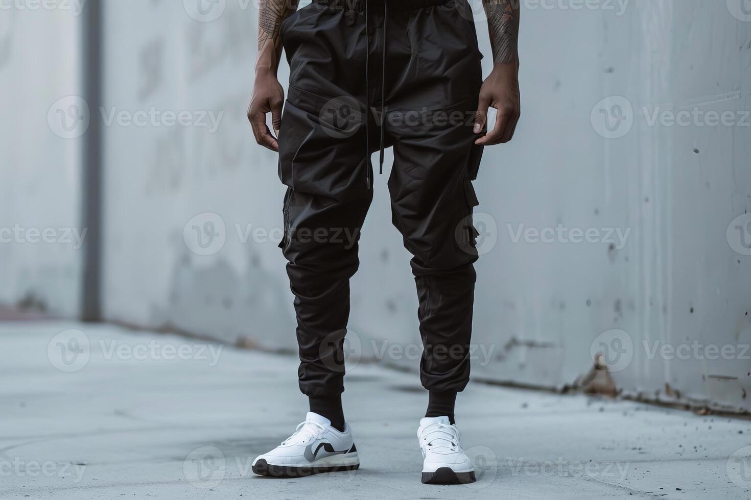 Young urban man posing wearing black cargo pants and white sneakers photo