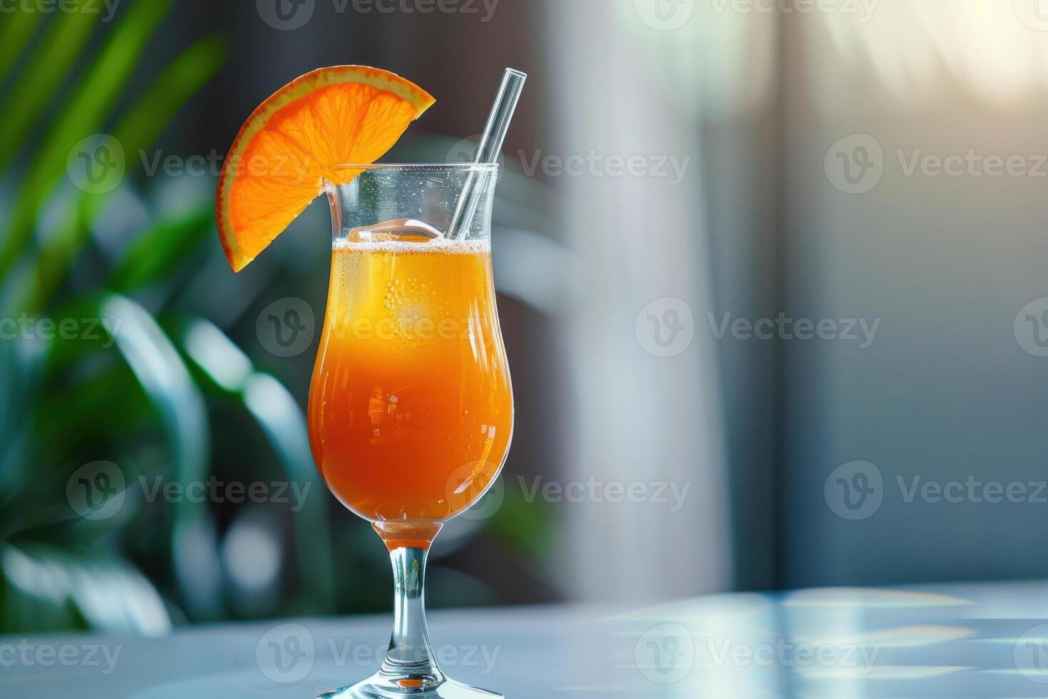 Orange cocktail standing on a bar with tropical plants in the background photo