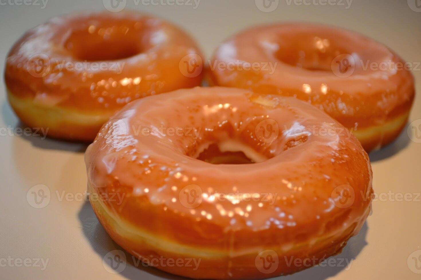 Three delicious glazed doughnuts arranged with a selective focus on a neutral background photo