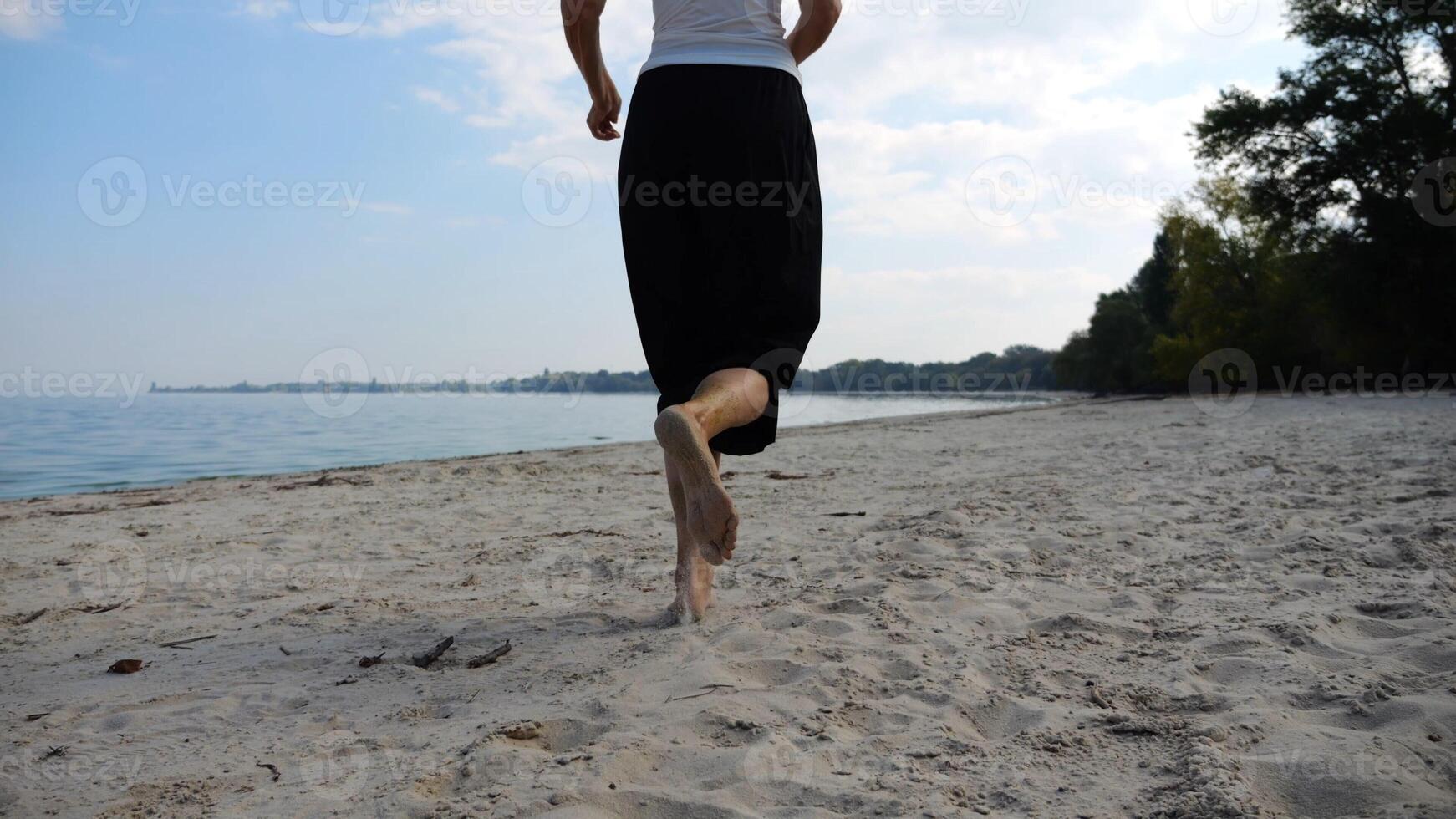 Bare feet of adult woman jogging on sand at the beach with seascape at background. Female legs running along sea shore. Happy lady spending time near ocean coast. Concept of summer vacation photo