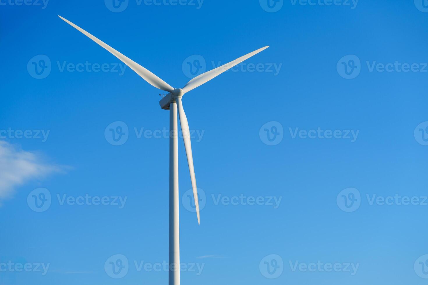 A lone white windmill stands tall against a clear blue sky, symbolizing the beauty of renewable energy. This wind turbine represents an eco-friendly source of power, contributing to a sustainable future. photo