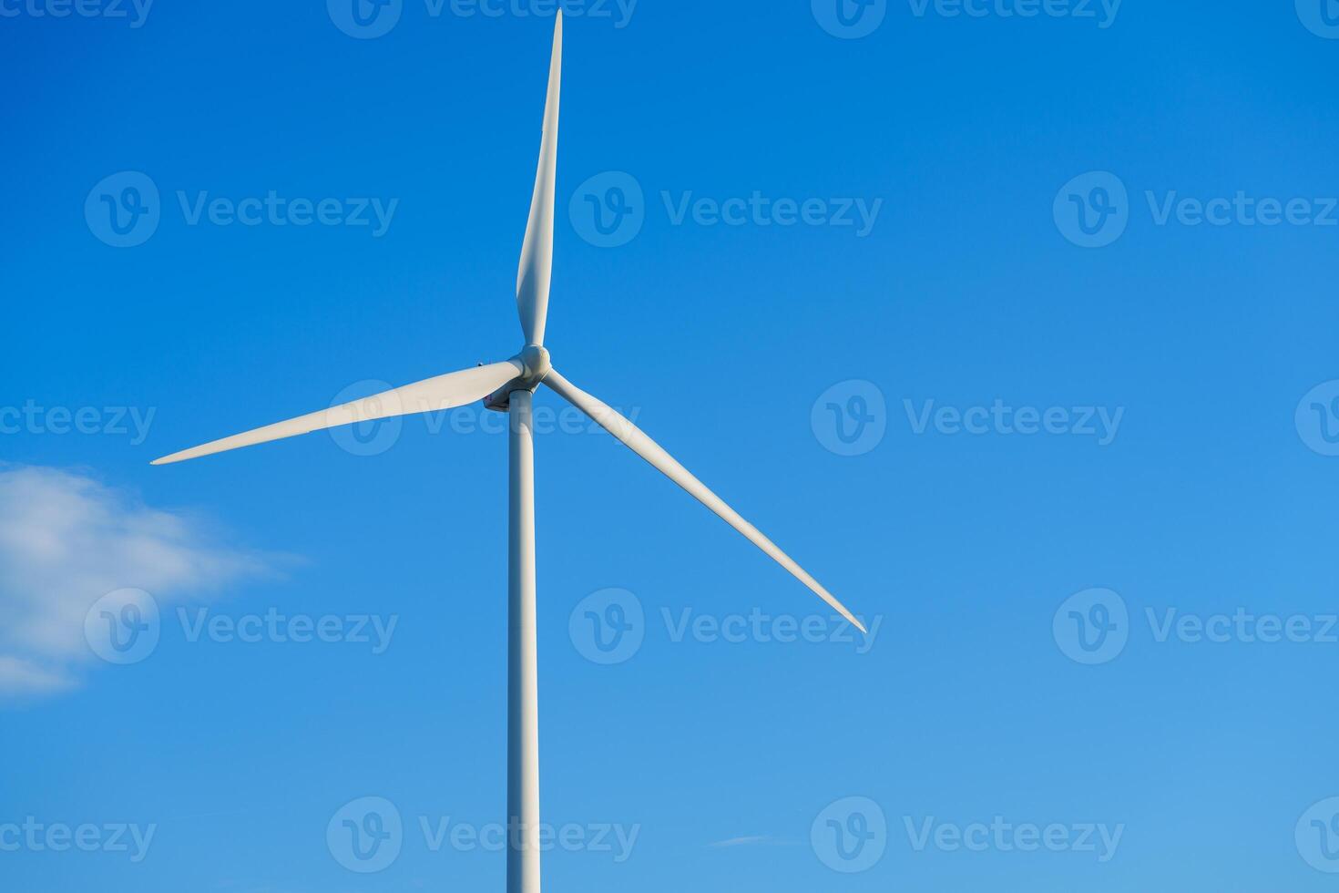A large white wind turbine with three blades towers against a clear blue sky, symbolizing clean energy. It harnesses wind power for sustainable electricity generation, contributing to a greener future. photo