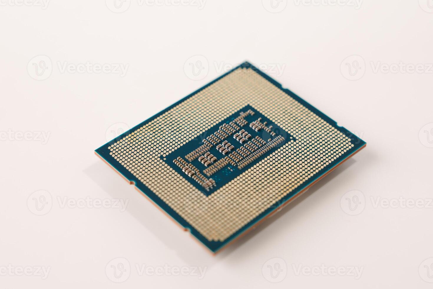 The image features the back of a computer processor with gold pins, set against a white background. This small square chip connects to the motherboard, executing computer program instructions. photo