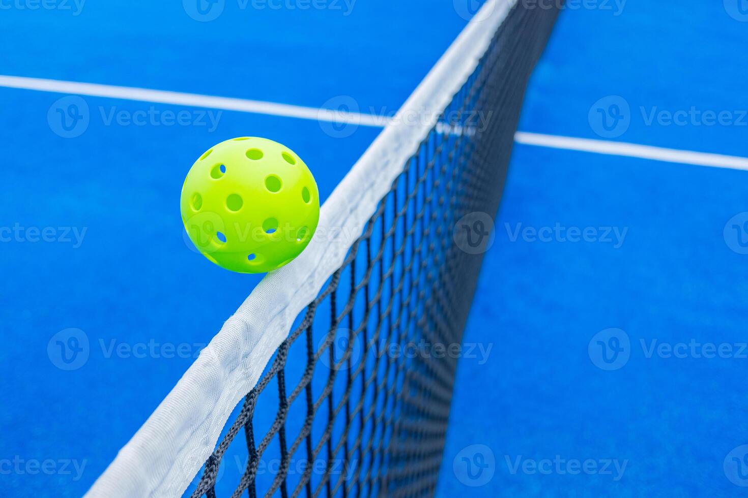 Pickleball ball over the net of a blue court. photo