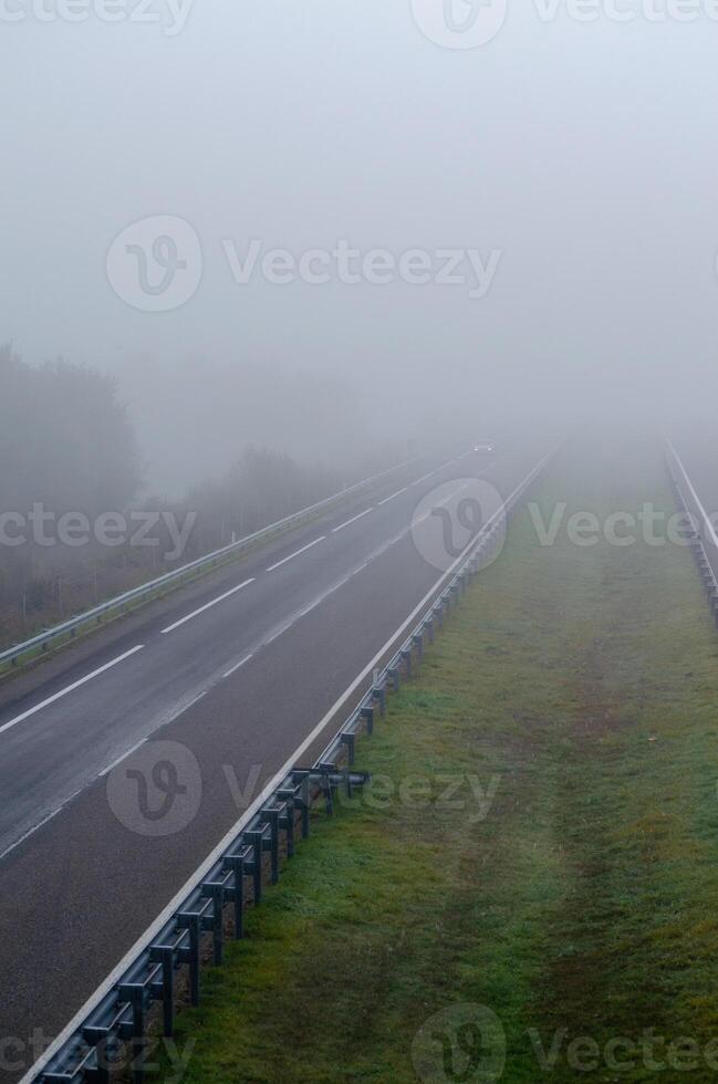 A car drives through fog on a freeway with little traffic. Highway with no traffic on a foggy day. Galicia. Spain photo