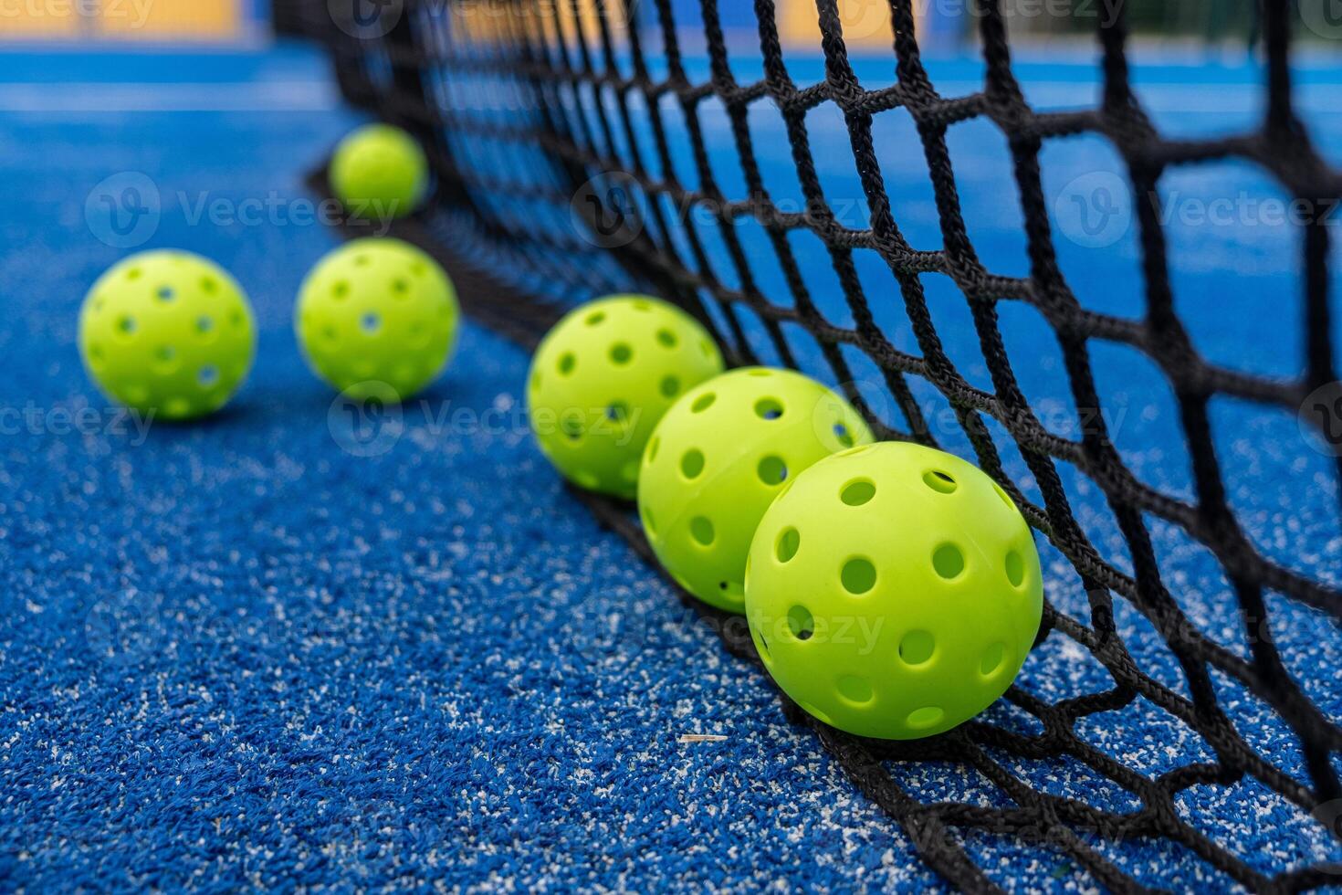 Green pickleball balls at the base of the net, new racket sport concept photo