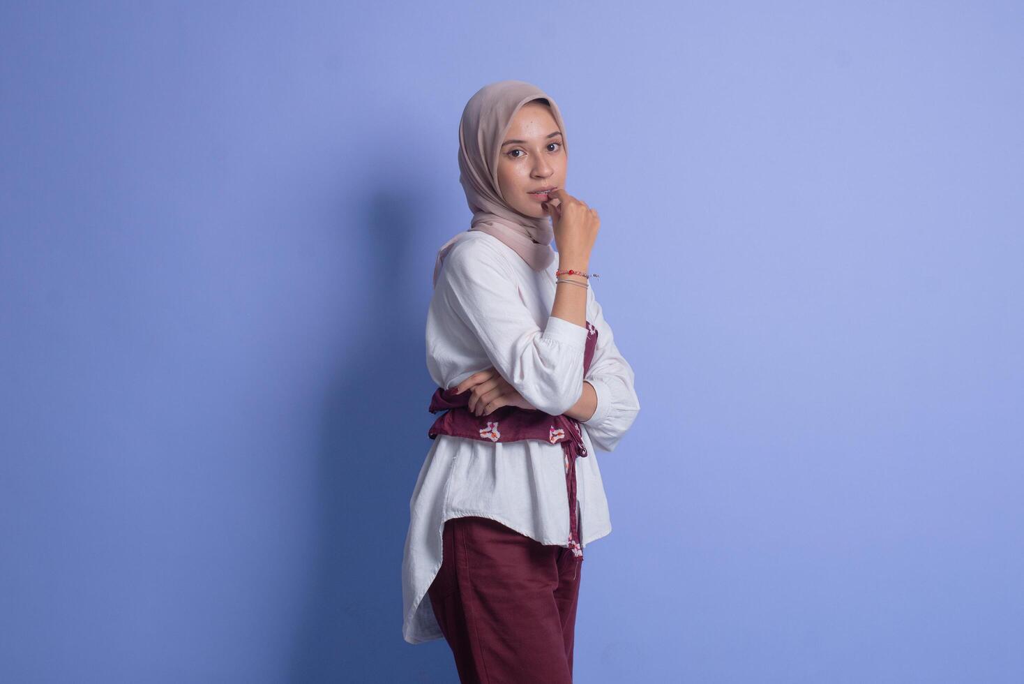 Young muslim woman wearing hijab posing against blue background photo