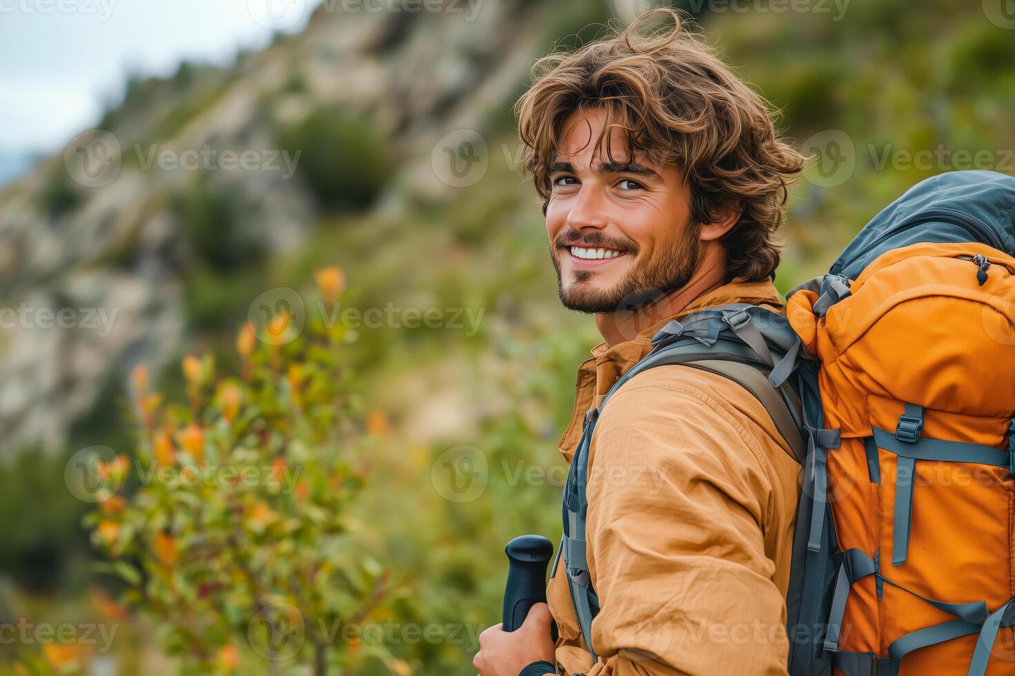 A man with a backpack smiles while hiking photo