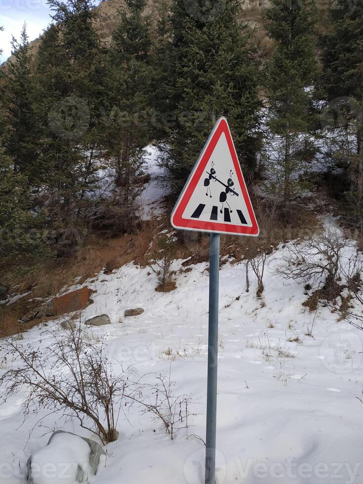 Warning sign alerting travelers to the presence of crossing reindeer in a snowy forest landscape during wintertime photo