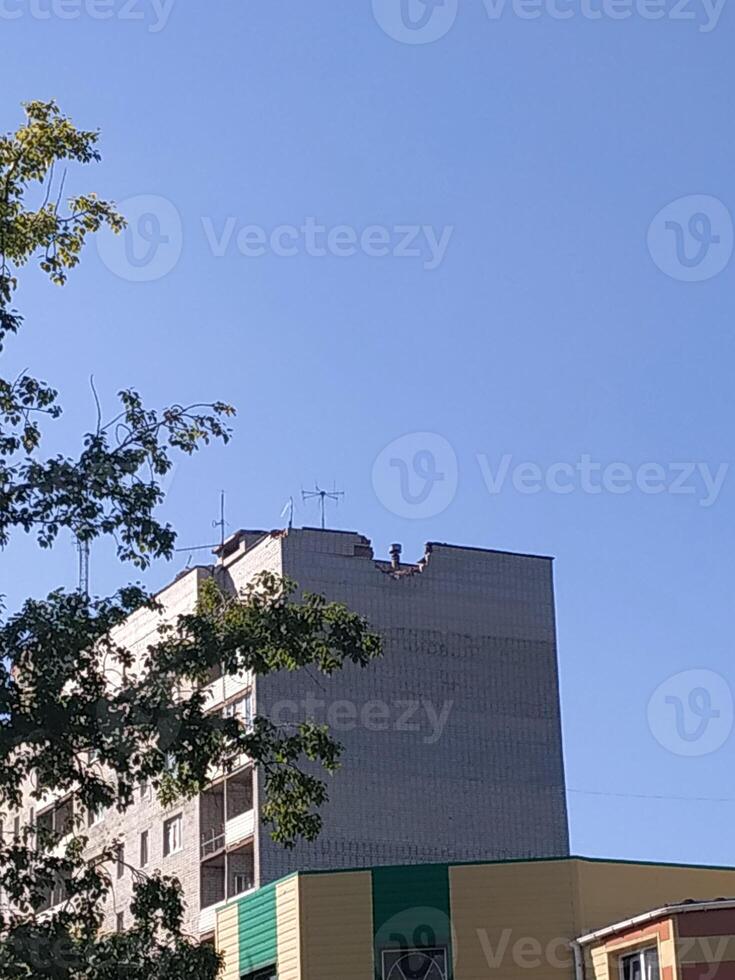 A bright blue sky frames the top of a concrete building with antennas in an urban landscape on a sunny day photo