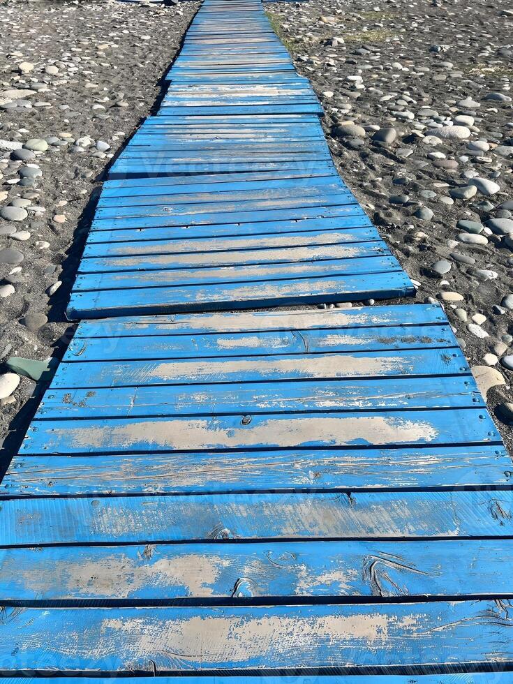 Weathered blue wooden path on rocky terrain creating a rustic and coastal outdoor walkway photo