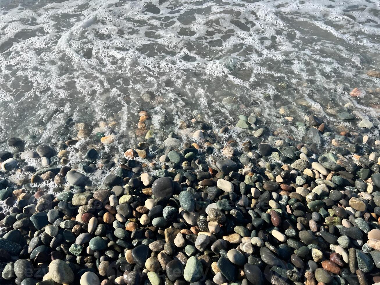 Gentle ocean waves lapping against a colorful pebble shore creating a serene coastal atmosphere photo