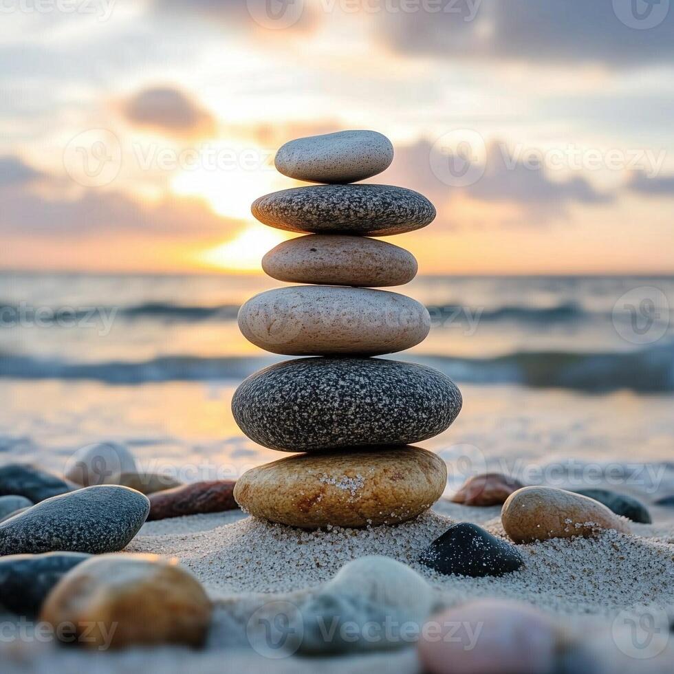 Balanced stones on sandy beach at sunset with calm ocean waves and soft golden light creating a peaceful scene photo