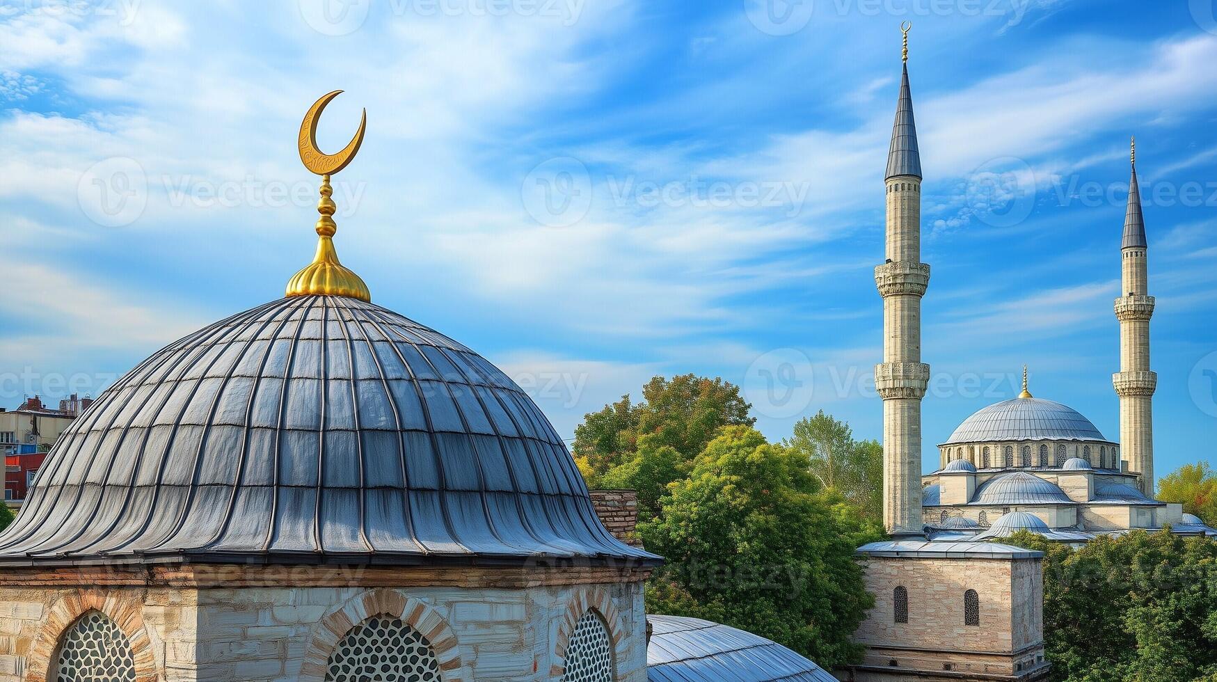 Beautiful mosque with domes and minarets surrounded by greenery under a bright blue sky with soft clouds photo