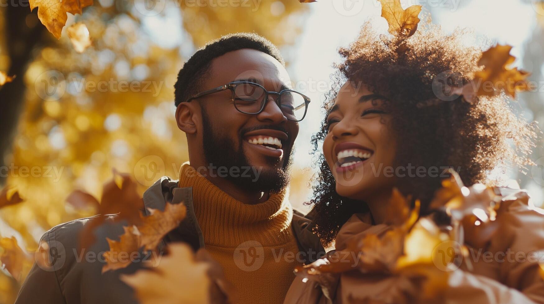 Happy couple smiling and embracing amidst golden autumn leaves, enjoying a joyful and romantic moment outdoors photo