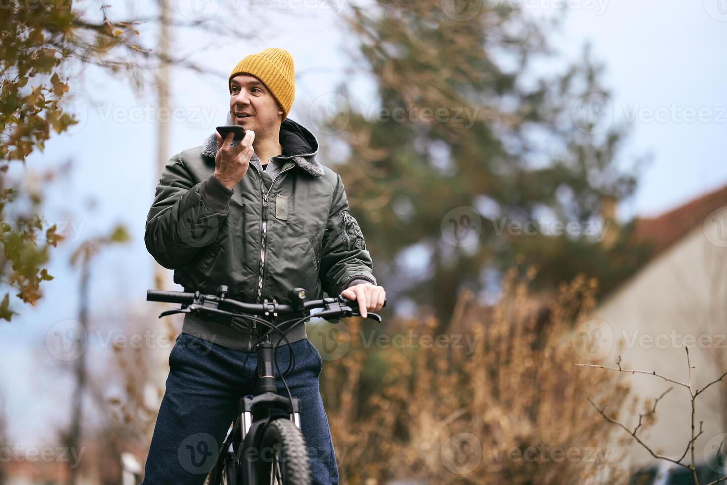 Man Using Cell Phone while Standing Next to Bike photo
