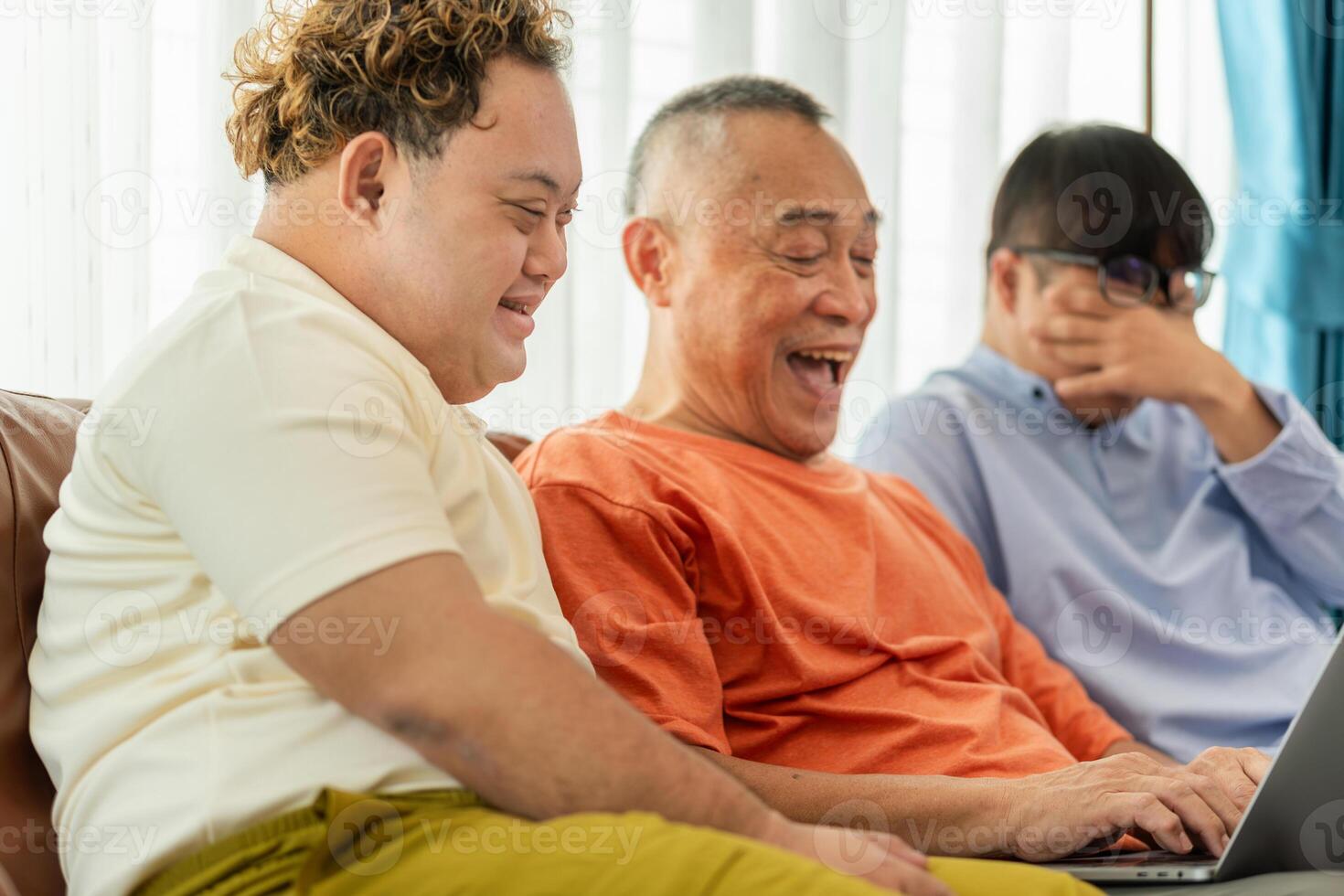 Senior asian man having a good time sitting on couch at home with adult son, Cheerful grandfather and grandson using laptop doing a call in living room photo