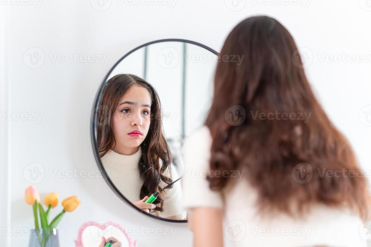 Teenage girl applying makeup, Teenage with freckle face applying makeup in front of a mirror at home photo