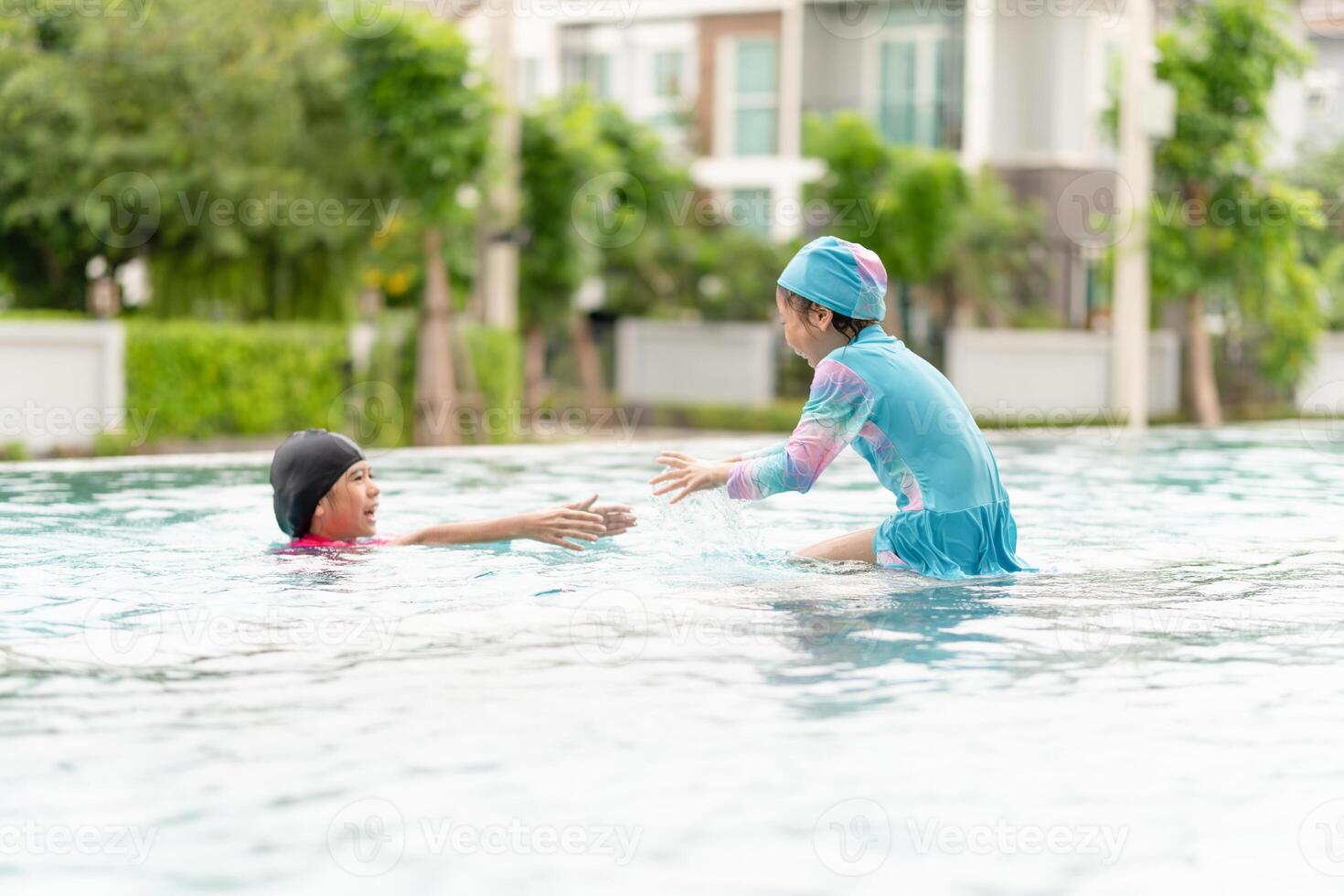 Asian children in swimsuit playing in swimming pool, Asian kids girl playing and having fun in swimming pool photo