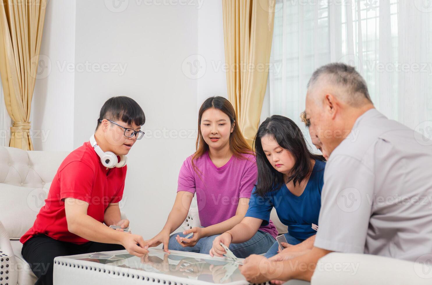 Senior man and grandchild relaxing in living room, Grandchild interacting with friends and playing cards with grandparents at home, Asian family photo