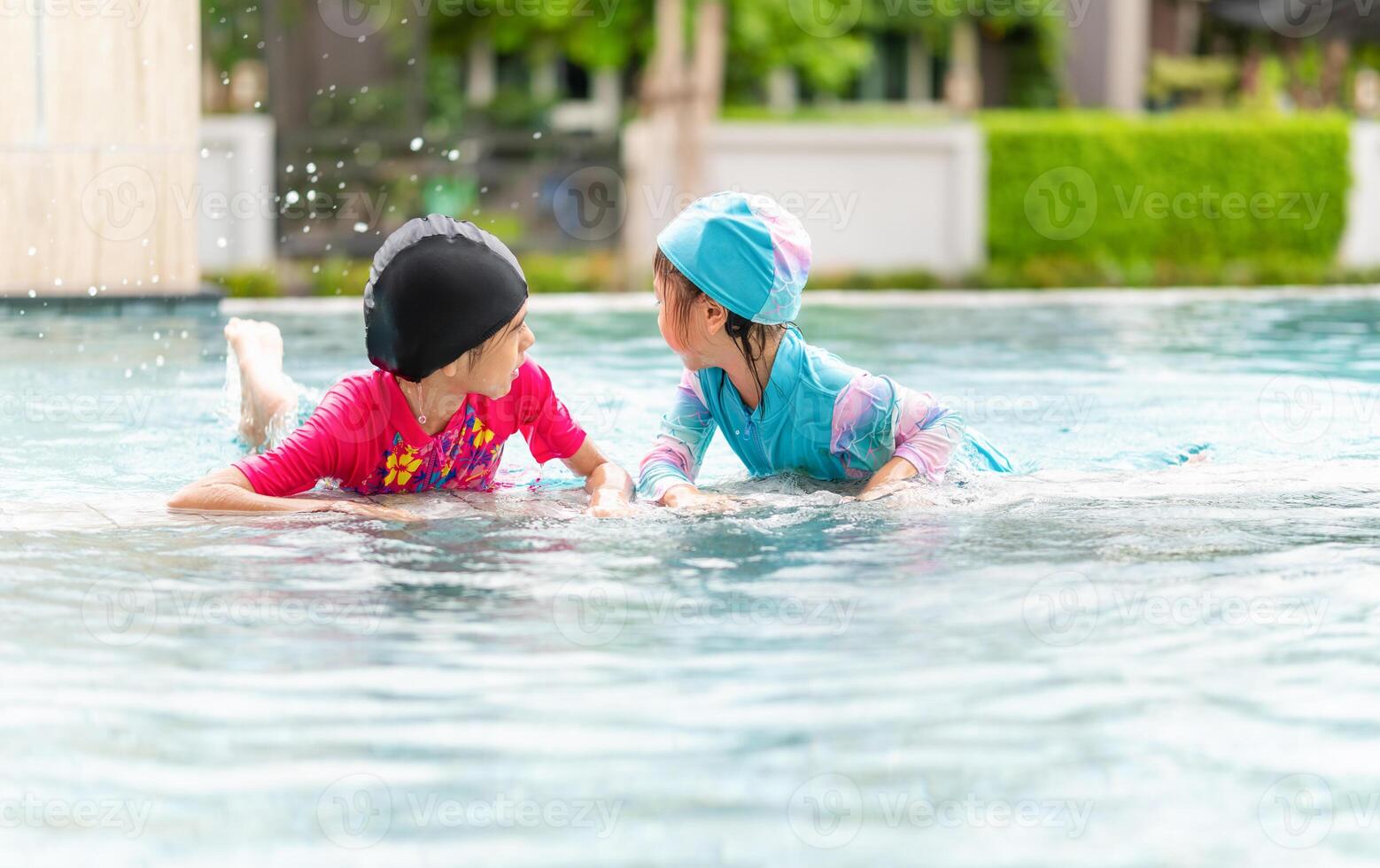 Asian children in swimsuit playing in swimming pool, Asian kids girl playing and having fun in swimming pool photo
