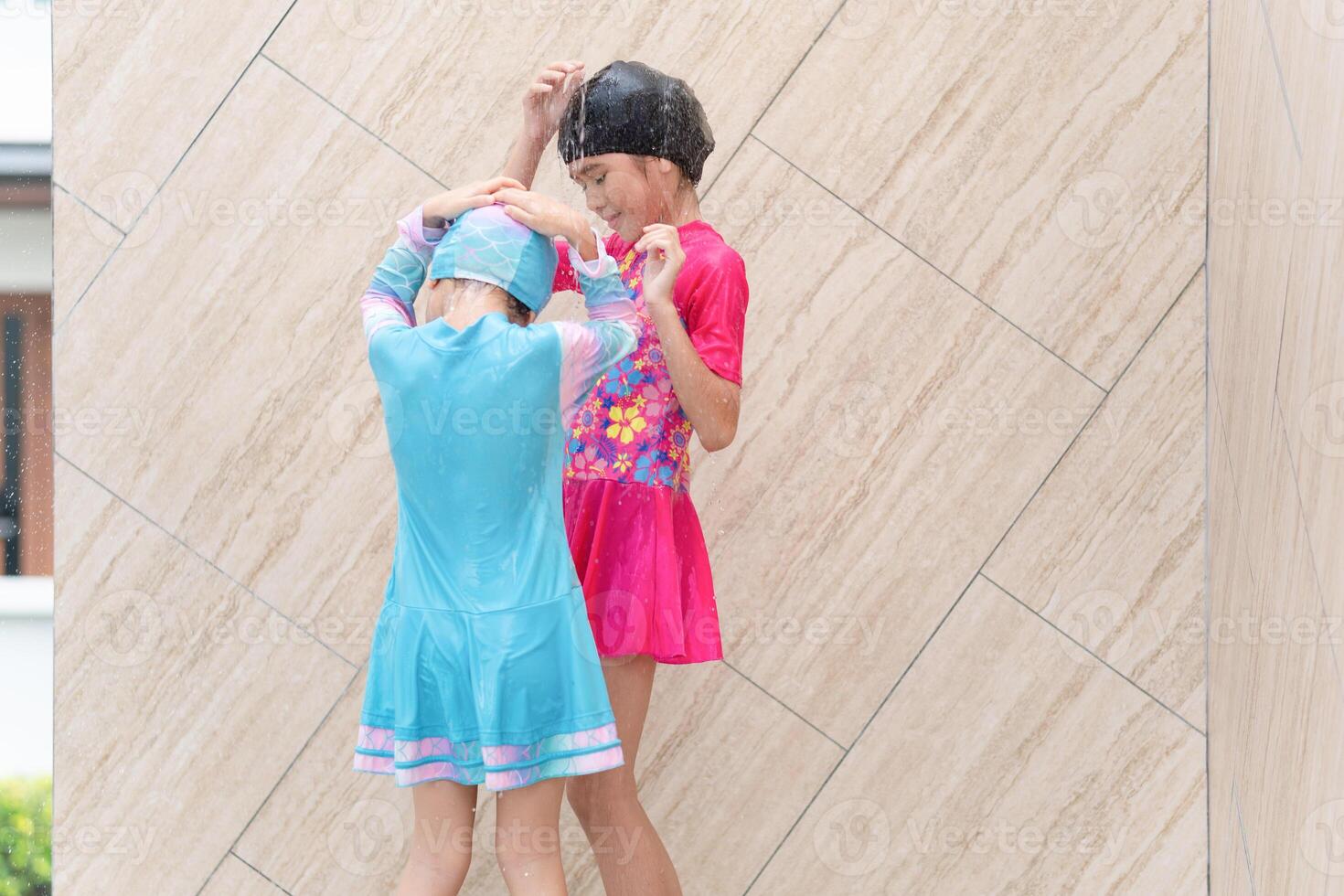 Kid girls washes under beach shower, Children taking a shower beside an outdoor swimming pool photo