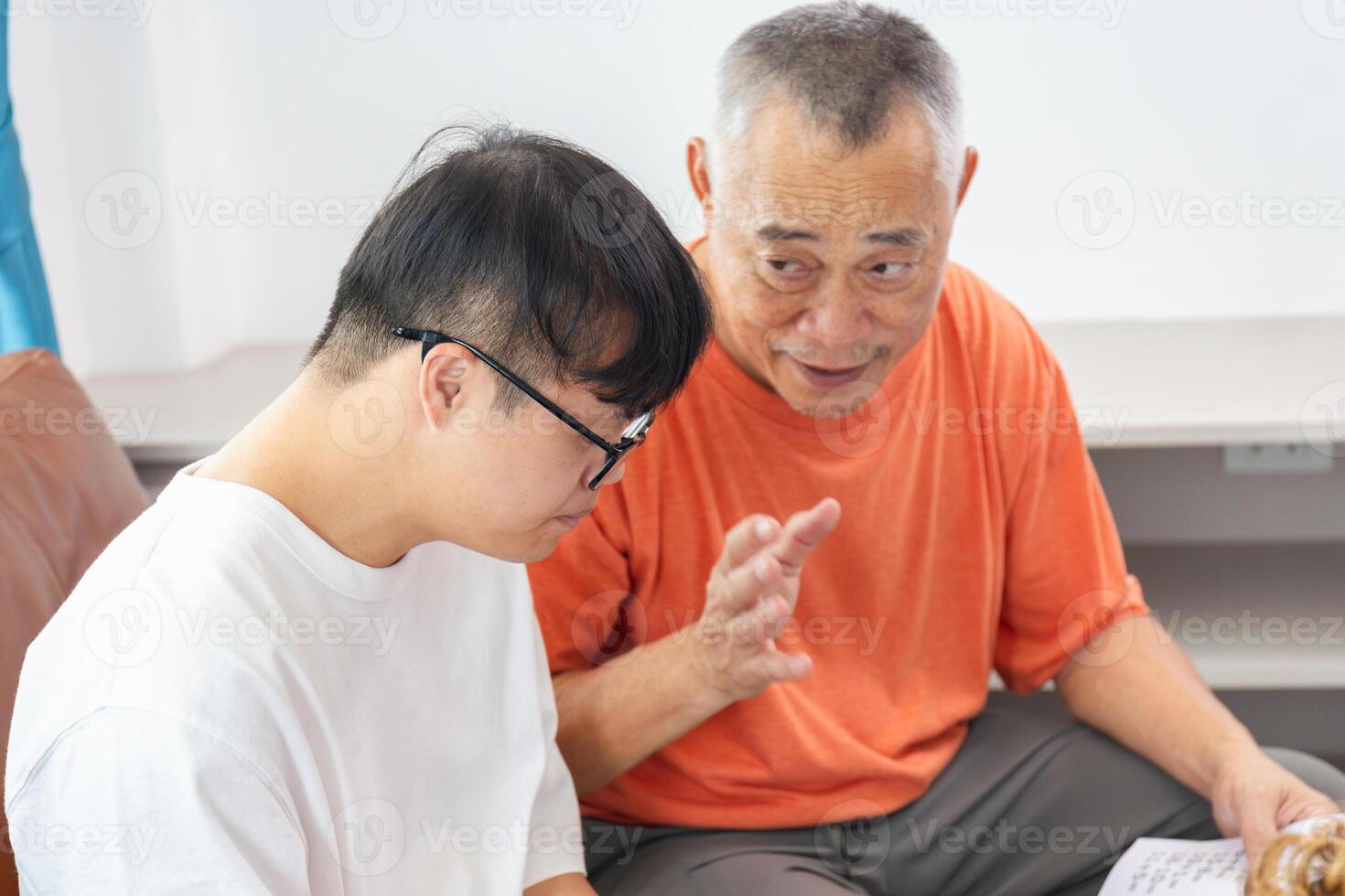 Asian man listen to senior man talking seated on sofa at home, speaking spend time together at home photo