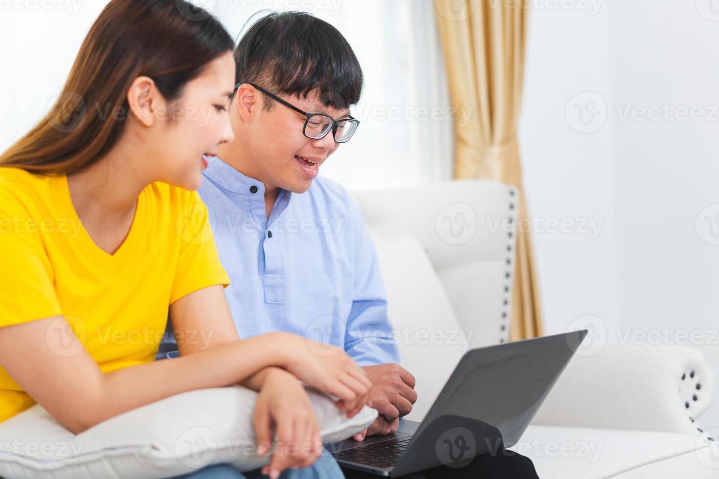 A group of friends using laptop doing a call in living room, Young man and woman sitting on sofa and using a laptop photo